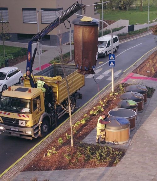 waste collection truck emptying underground trash bin