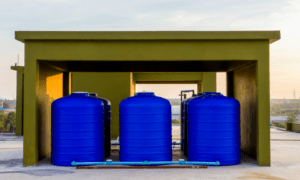 Three blue water tanks next to each other under the roof.