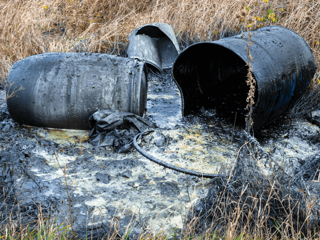 Old barrels with spilled liquid on the ground.