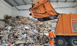 A waste truck dumping garbage into a landfill located inside a building.