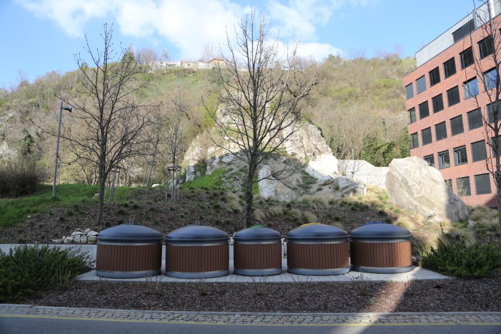 Semi-underground bins for different types of waste at a garbage stand.