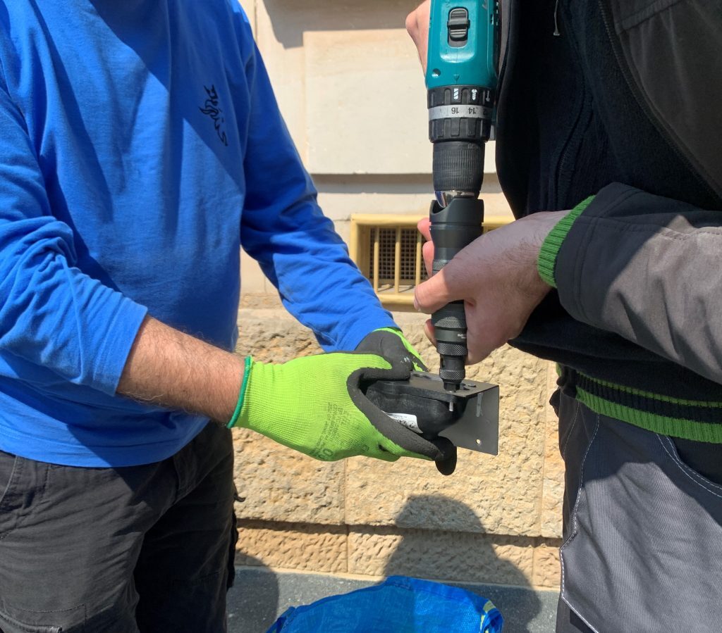 Two technicians installing fill-level monitoring sensor into the street bins.