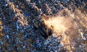 Truck driving on the landfill full of garbage, waste and trash